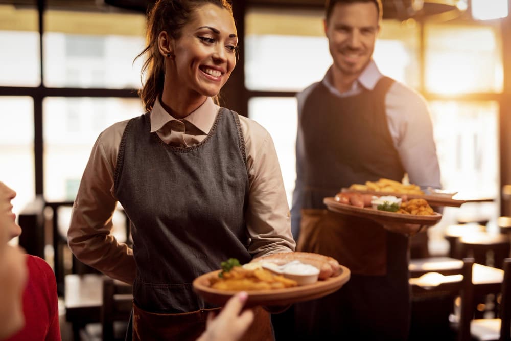 dois-garcons-servindo-almoco-e-servindo-comida-para-suas-rajadas-em-uma-taverna-o-foco-esta-na-garconete-feliz